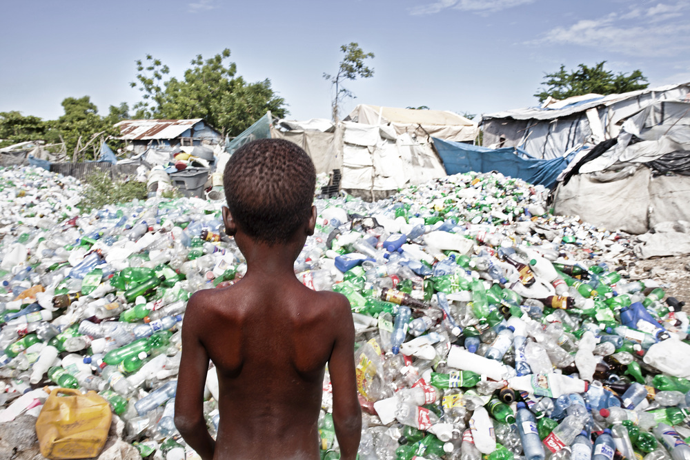 Boy looking at heaps of plastic waste